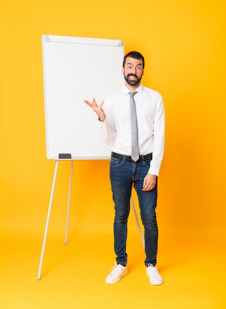 Coup de pied d'homme d'affaires donnant une présentation sur tableau blanc sur jaune faisant des doutes geste