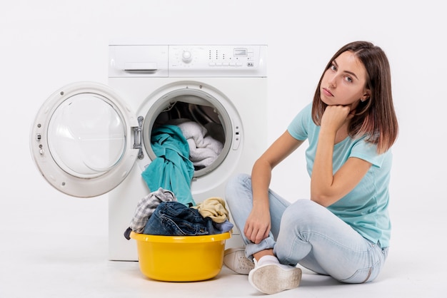 Photo coup plein femme contrariée assis près de la machine à laver