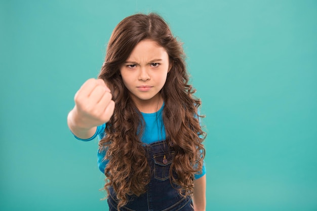 Coup de poing douloureux. Enfant sérieux menaçant. Vous frapper au visage. Arrêtez le mouvement d'intimidation. Fille menaçante avec le poing. Menace d'attaque physique. Notion d'agression. Fille agressive menaçant de battre.