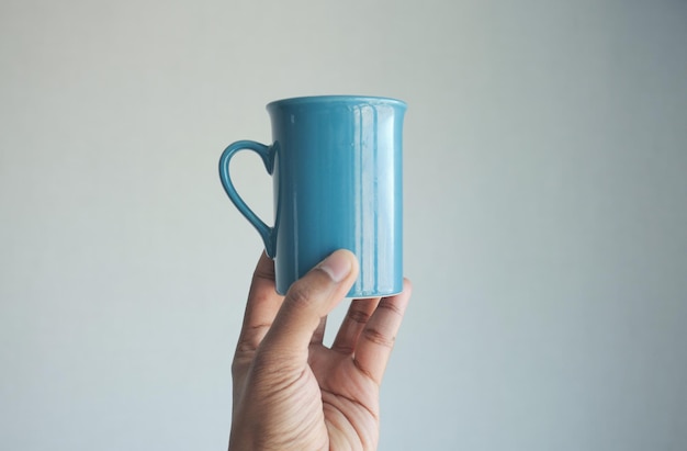 Coup de pov d'une main d'homme tenant une tasse de couleur bleue