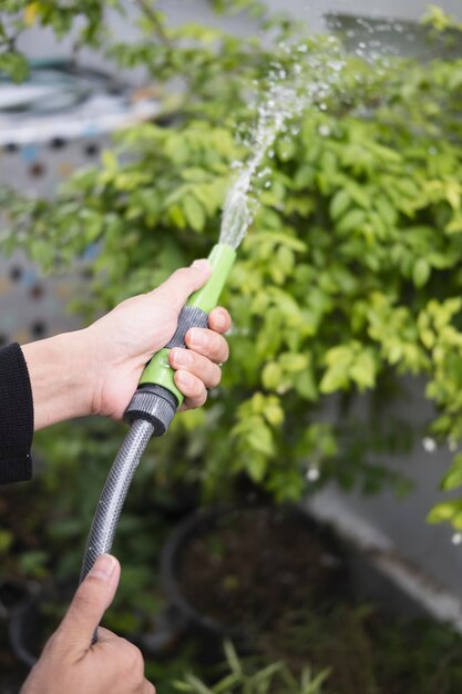 Coup recadré homme tenant un tuyau d'arrosage des arbres à la maison