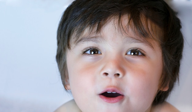 Coup de tête de mignon petit garçon regardant la caméra avec de beaux yeux bruns