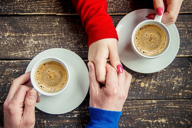 Coupe boisson pour le petit déjeuner entre les mains des amoureux. Mise au point sélective.