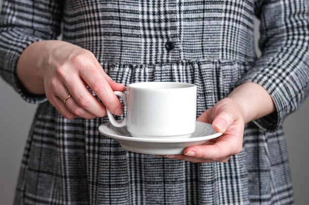 Photo coupe de café blanche et soucoupe dans des mains féminines maquette pour la conception