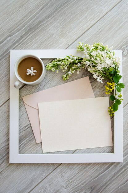 Coupe de café cadre en bois blanc et maquette et copyspace enveloppe rose pastel et carte blanche