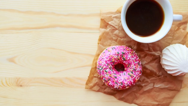 Photo coupe de café en zéphir blanc et donut rose sur le dessus de la table en bois vue copier l'espace pour le texte