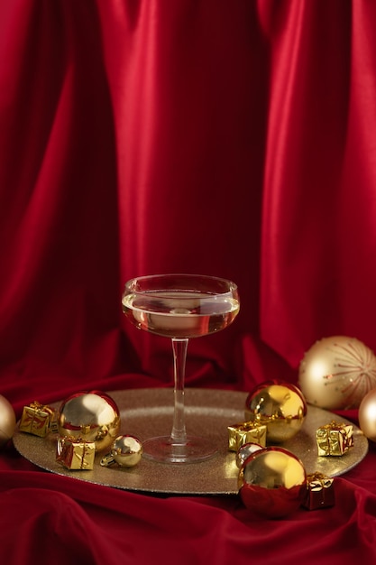 Coupe de champagne avec des ornements de Noël dorés sur un rideau de velours rouge