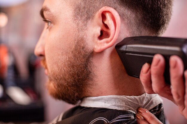 Coupe de cheveux gros plan. Mains tenant une tondeuse à cheveux.