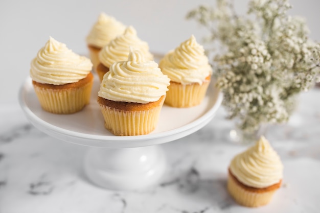 Coupe du gâteau sur le stand de gâteau avec des fleurs sur fond texturé