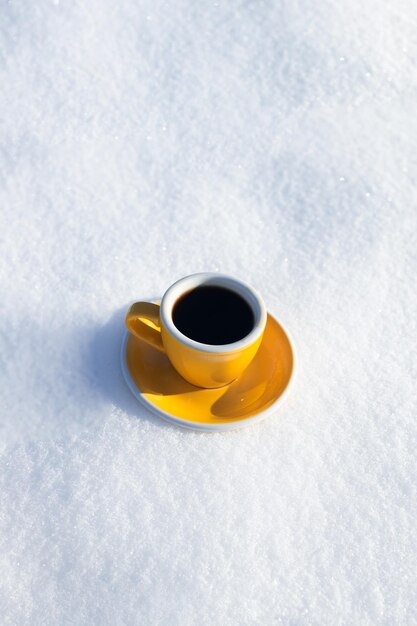 Photo coupe jaune d'hiver avec du café chaud ou du thé sur la neige en plein air par une journée ensoleillée avec du froid