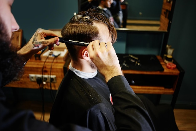 Coupe à la main avec des ciseaux l'homme en gros plan Barbershop