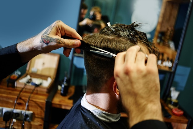 Coupe à la main avec des ciseaux l'homme en gros plan Barbershop