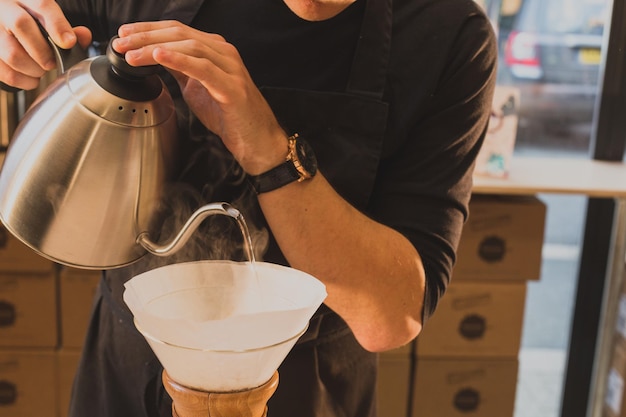 Coupe médiane d'un homme versant de l'eau dans un filtre à café