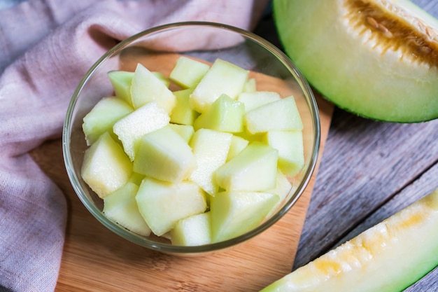 Photo coupe de melon vert doux frais dans un bol en verre sur la table en bois. concept de fruits ou de soins de santé.