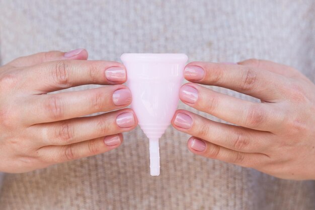 La coupe menstruelle est tenue par les mains de la femme Mise au point sélective