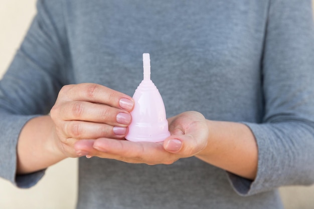 La coupe menstruelle est tenue par les mains de la femme Mise au point sélective