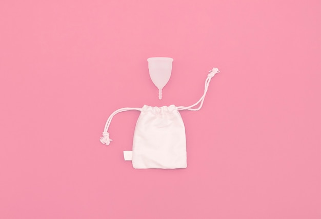 Coupe menstruelle pour l'hygiène intime, sac en lin pour ranger la coupe. Fond rose avec espace copie.