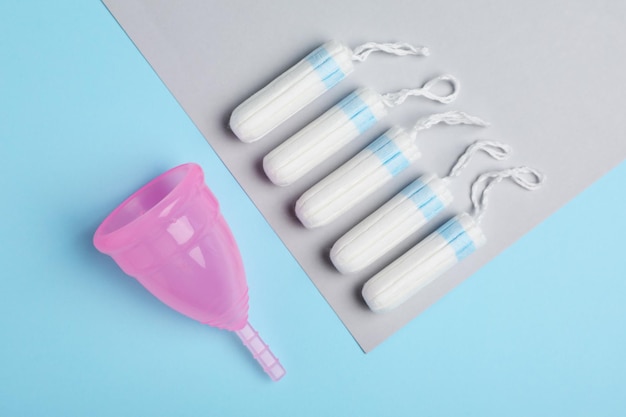 Coupe menstruelle et tampons sur fond de couleur à plat