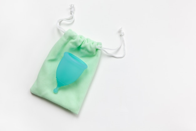 Photo coupe menstruelle turquoise sur petit sac vert sur fond blanc