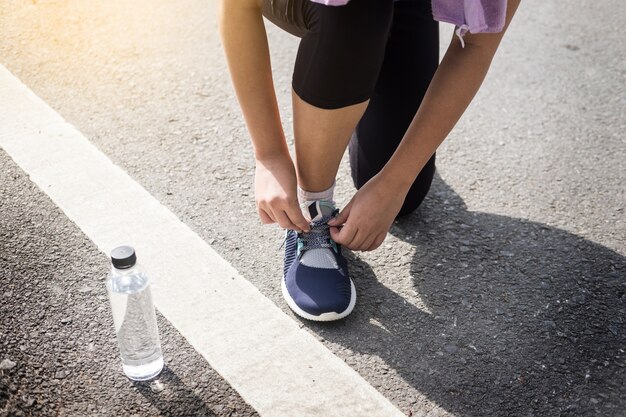 Coupe recadrée de jeune femme coureur serrant la chaussure de course