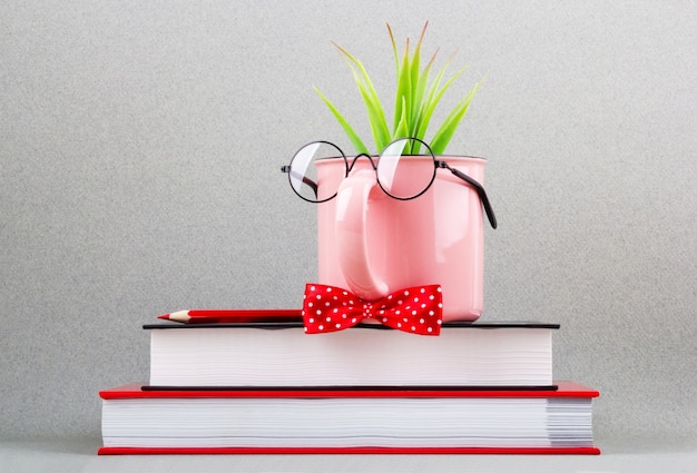 Coupe rose sous une pile de livres.