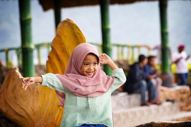 Coupe roseCute fille musulmane indonésienne portant le hijab souriant pour la caméra sur le perroquet cacatoès des enfants