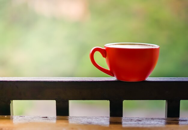 Coupe rouge de café sur rail de balcon en acier noir avec arrière-plan flou