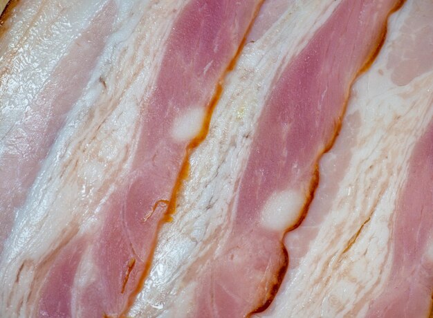 Coupe sinueuse pliée en rouleaux Porc sur une planche de cuisine Nature morte de viande Apéritif de poitrine de porc Fond de bacon