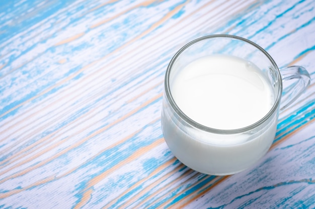 Photo coupe en verre de lait sur une table en bois bleue. espace texte. concept de régime laiteux.