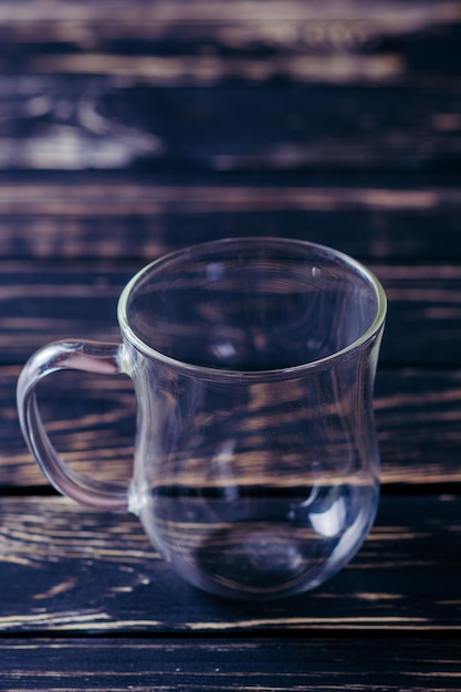 Coupe en verre vide sur la table en bois sombre et fond noir