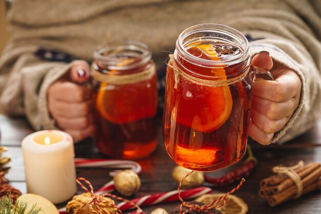 Coupe de vin chaud dans les mains de la femme sur une table en bois