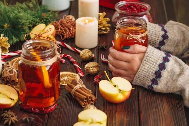 Coupe de vin chaud dans les mains de la femme sur une table en bois