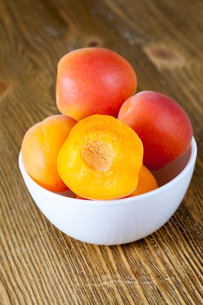 Couper les abricots dans un bol en verre blanc, fruits délicieux et sains, abricots rouges et jaunes, gros plan de nourriture