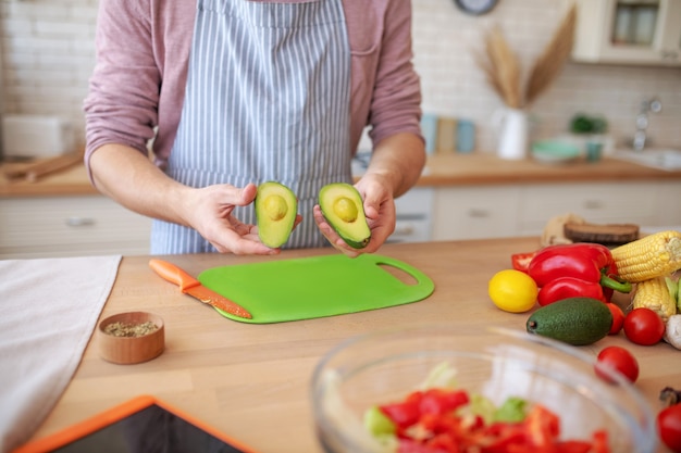 Couper un avocat. Un homme tenant deux morceaux d'avocat sans os