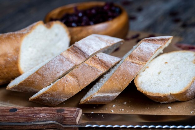 Couper la baguette de blé frais en plusieurs morceaux de baguette fraîche douce tranchée sur une planche à découper et une table