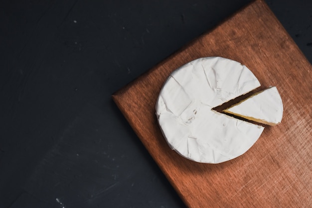 Couper le camembert se trouve sur une assiette de cuisine en bois