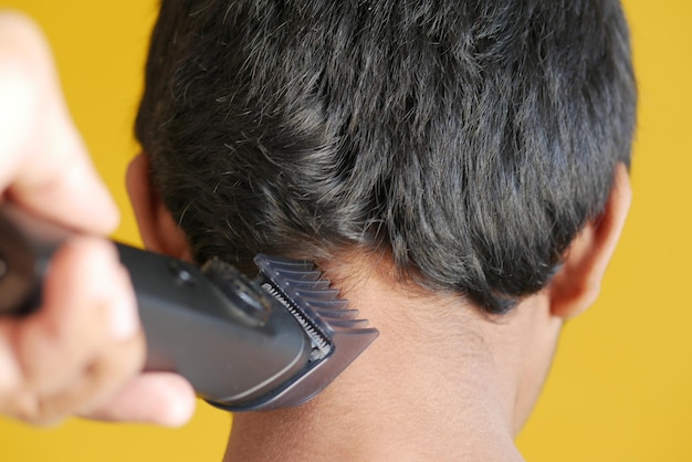 Couper Les Cheveux Avec Une Tondeuse à Cheveux Sur Fond Jaune