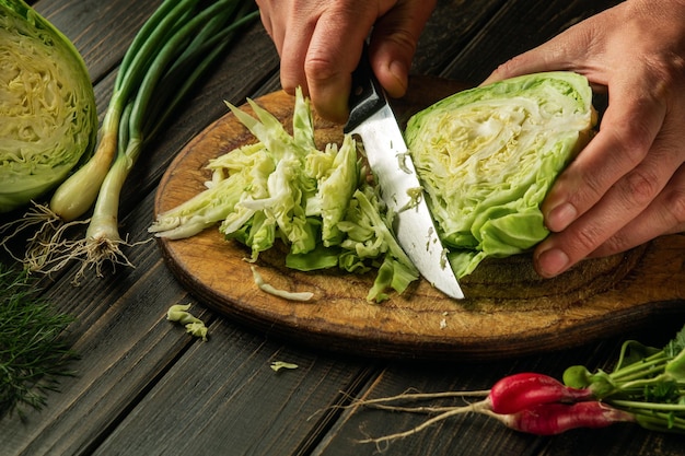 Couper le chou frais par les mains du chef avant de préparer des plats nationaux ou végétariens Nourriture paysanne