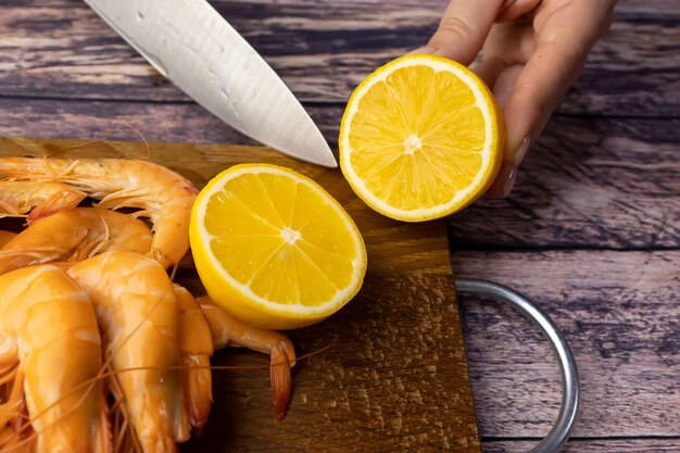 Couper un citron près de crevettes bouillies sur un support en bois