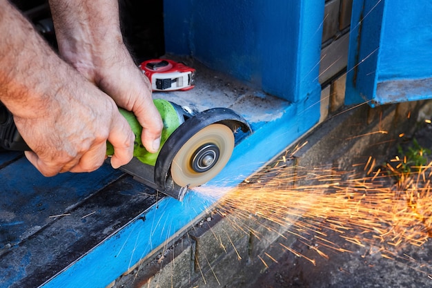 Photo couper un coin métallique avec une scie circulaire avec des éclaboussures d'étincelles. travaux de jardin