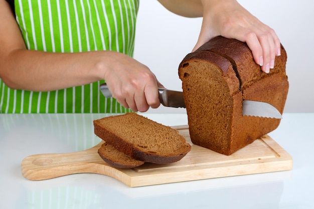 Couper du pain sur planche de bois isolé sur blanc