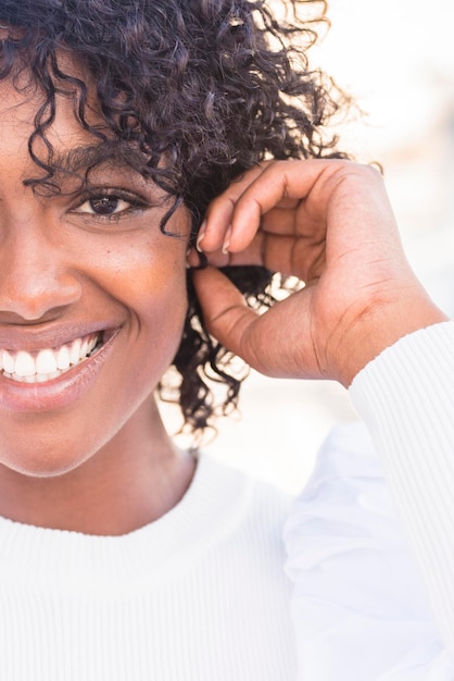 Couper l'image de la composition de la moitié du visage avec une jolie jeune fille noire souriante grande et regardant la caméra sur fond blanc Photo de tête de femme modèle Afro Concept de diversité et de bonheur