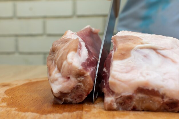 Photo couper un morceau de porc juteux avec un couteau de cuisine.