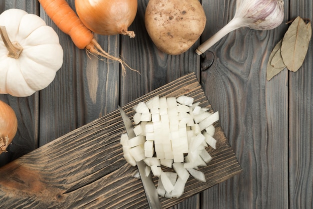 Couper l'oignon épicé blanc avec un couteau en cubes sur une planche en bois de cuisine