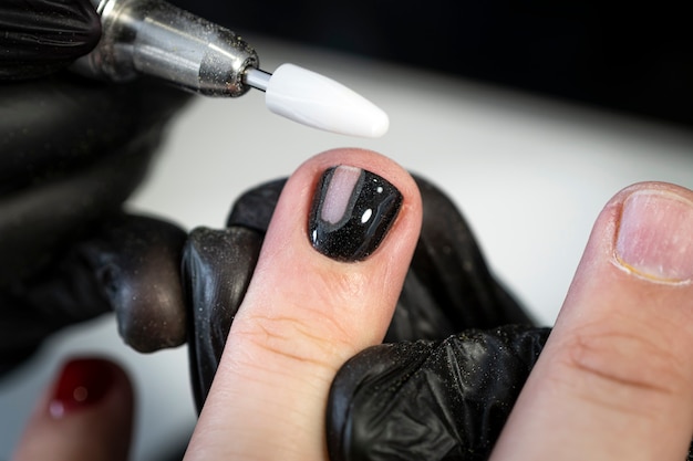 Couper les ongles sur la main d'un homme. Retrait de la manucure Le processus de coloration des ongles sur les doigts des hommes dans un salon de beauté. Une fille manucure donne une manucure à un mec