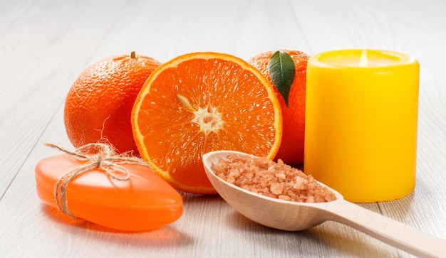 Couper l'orange avec une cuillère en bois de savon de deux oranges entières avec du sel de mer brun et une bougie jaune brûlante