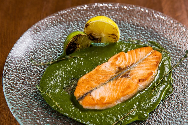 Couper le poisson au citron et sauce dans une assiette en verre sur une table en bois dans un restaurant de luxe