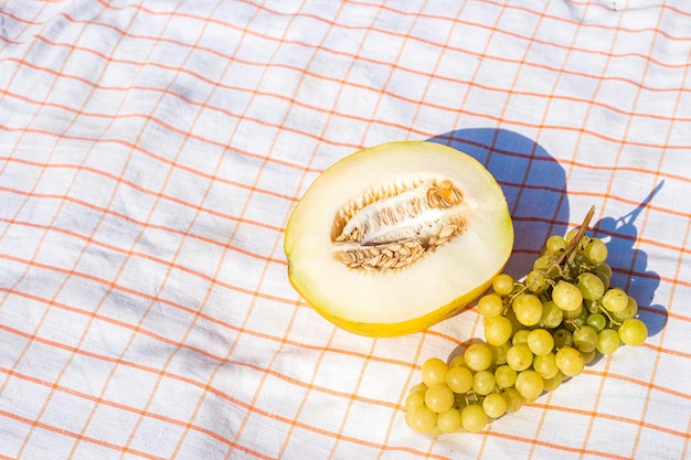 Couper des raisins de melon jaune sur la nappe de table vue supérieure à plat