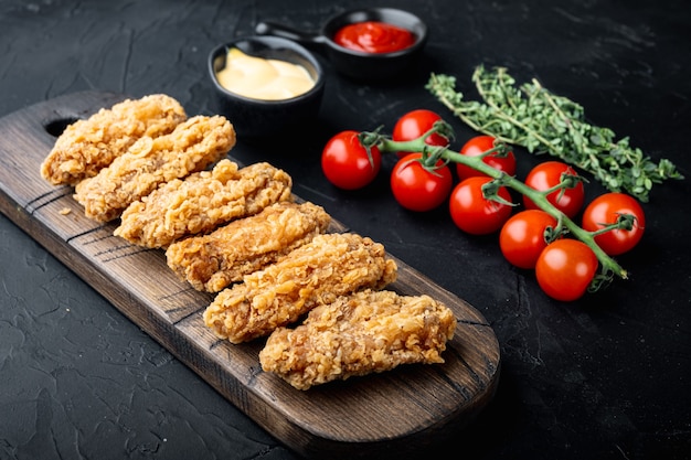 Coupes d'ailes de poulet panées frites épicées sur fond noir