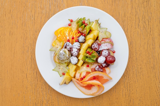 Coupes de fruits de pommes ananas kiwi et raisins saupoudrés de sucre glace